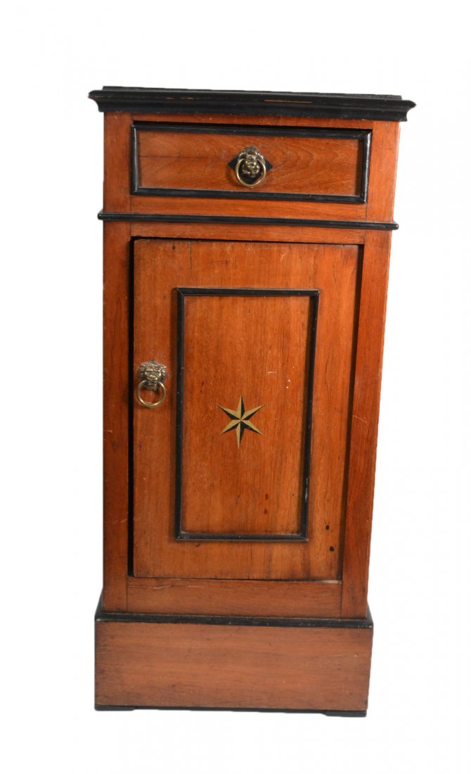 Vintage Bedside Stand: Mahogany stand with one drawer above one door bearing ebonized wood trim, lion's head pulls, and painted star accents. [14 1/2" W x 11 1/2" D x 30 7/8" H]. Wear throughout with cracks and losses to tr