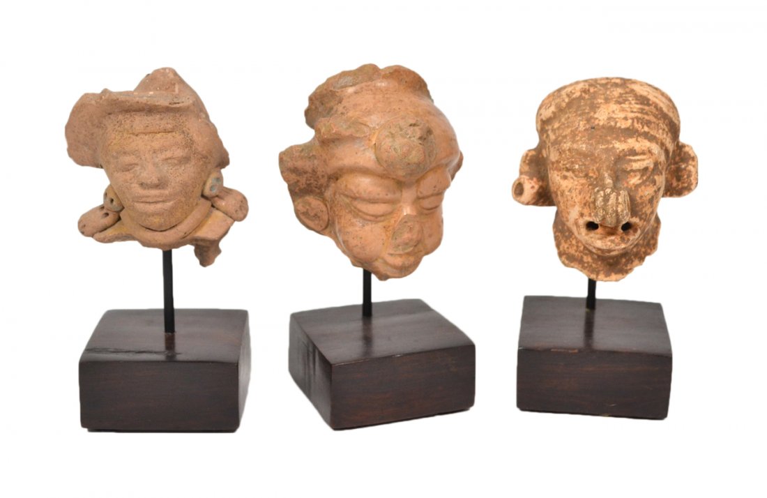 Three Mayan Terra Cotta Heads: Three Mayan terra cotta heads, each mounted on a metal stand on a rosewood base. [Largest head: 3 1/4" H].