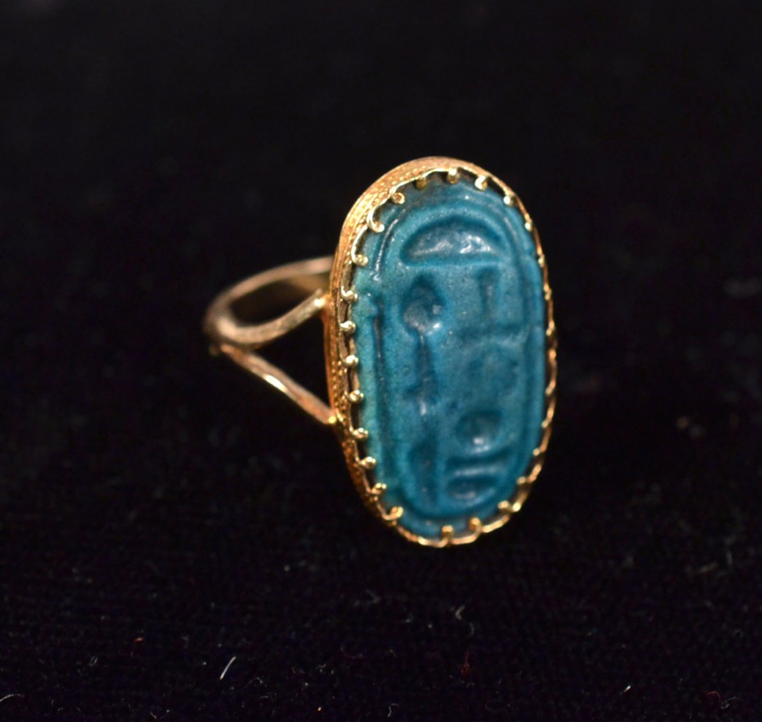 14k Gold Ring Mounted with Ancient Seal: 19th - 20th dynasty greenish blue faience cartouche seal incised "AMUN-RE ALL THE GOOD". Mounted in a modern gold setting. [7/8" L]. Wear commensurate with age.
