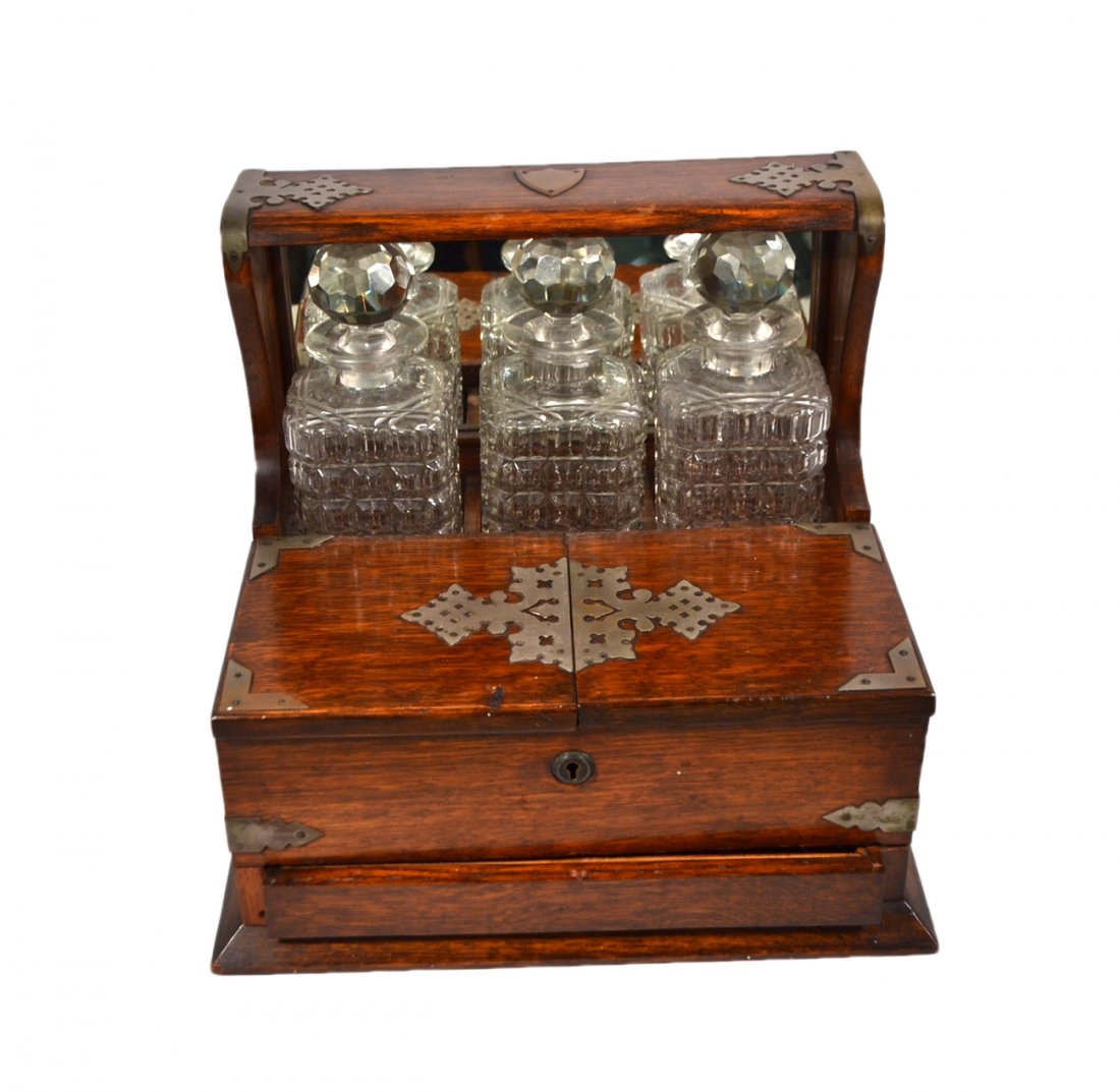Victorian Oak Tantalus: Brass mounted oak tantalus with three cut glass decanters and interior compartment for glasses and shallow drawer. [13 1/4" W x 11 1/4" D x 13" H]. Missing internal dividers. Otherwise good condition.
