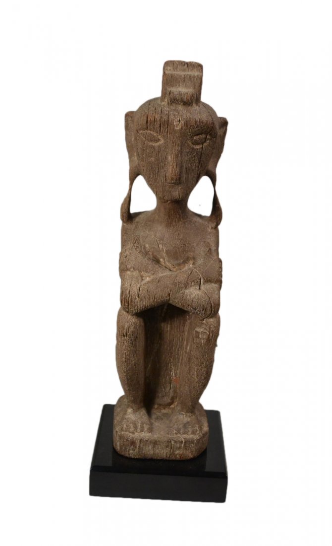 Tribal Art, Totem Figure: Carved exotic wood depiction of a seated figure with arms crossed and ceremonial headdress. [Figure only: 4" W x 3 3/4" D x 15 1/2" H; on black base: 16 7/8" H].