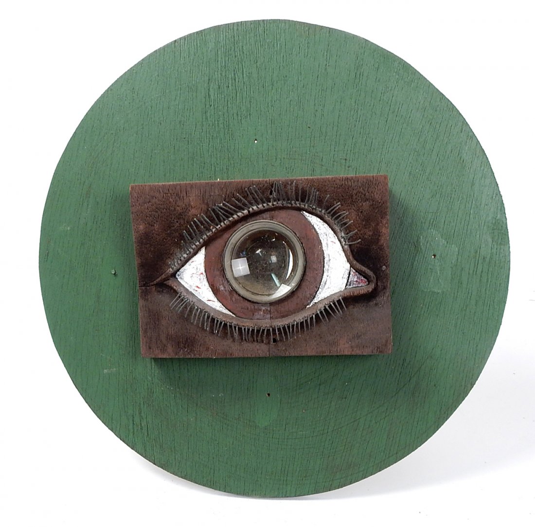 Wood & Bronze Sculpture - Door Peep Hole: Carved wood sculpture of an eye with convex lens "Door Peep Hole", having bronze wire lashes mounted on a painted green plywood circle.