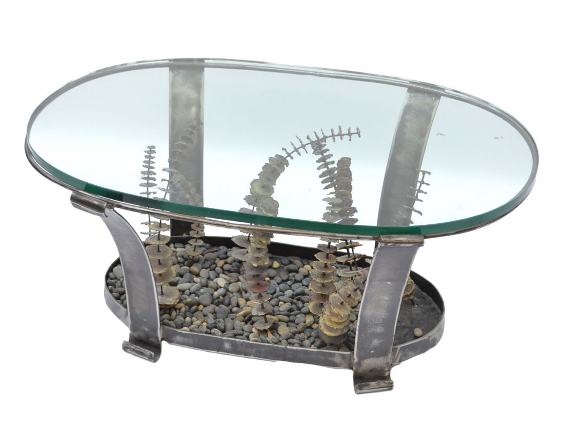 Silas Seandel Coffee Table: En suite with previous Lot 70. Glass and metal coffee table. Signed on one metal leg, "Silas Seandel." Base consists of a rock and metal sculpture. [36" W x 16" H]. Good condition.