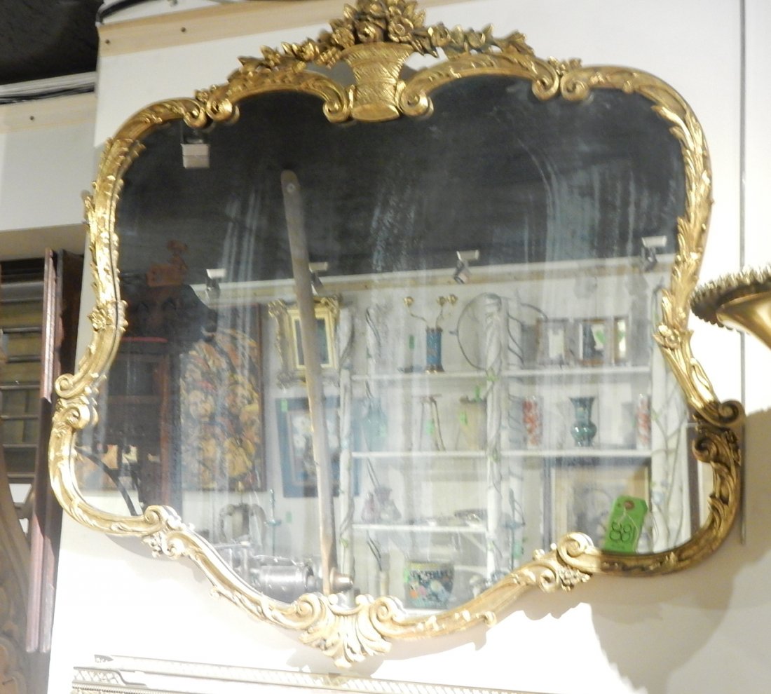 Gilt Mirror: Large gilded mirror with floral and scroll gilt ornamentation surrounding mirror. [43" W x 41" H]. Overall good condition, some minor loss to gilding. Chip to cornice, clouded glass.