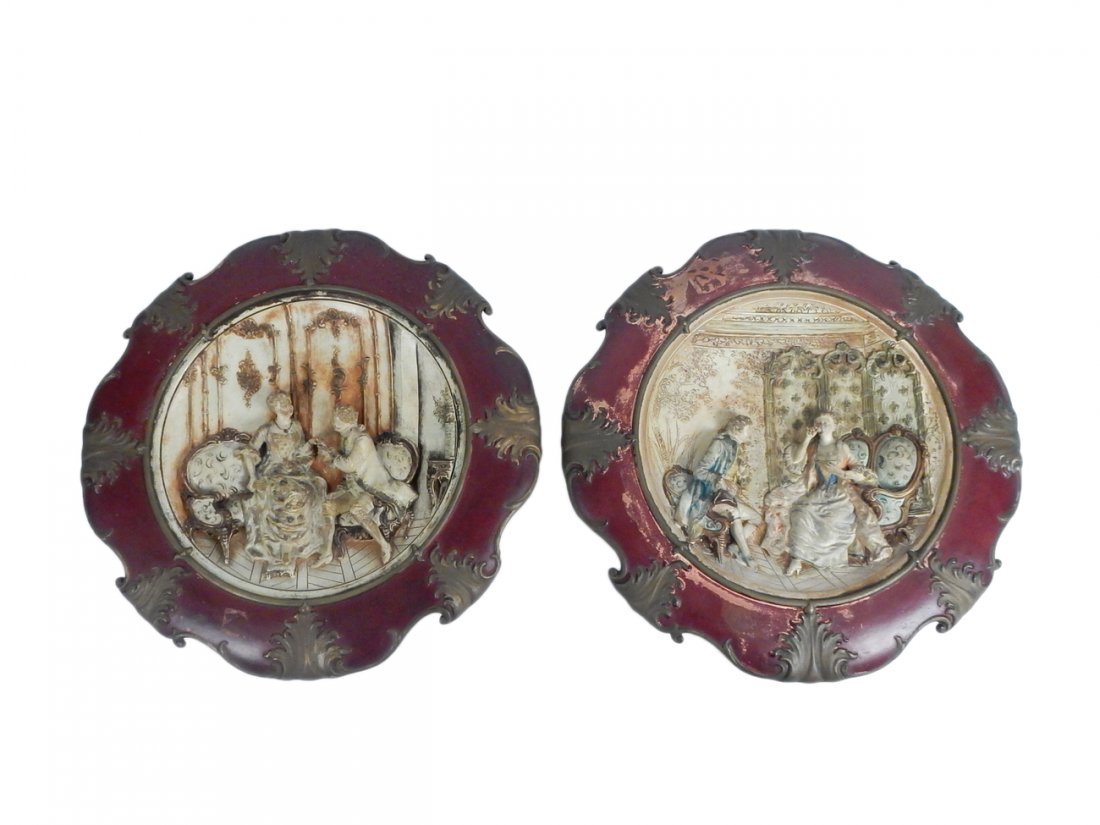 Pair of Ceramic Wall Chargers: Pair of large German ceramic wall chargers, featuring carved figural Rococo Revival onramentation. [19 1/2" Dia, 2" D approx.]. Paint loss, paint sprinkles on one charger.