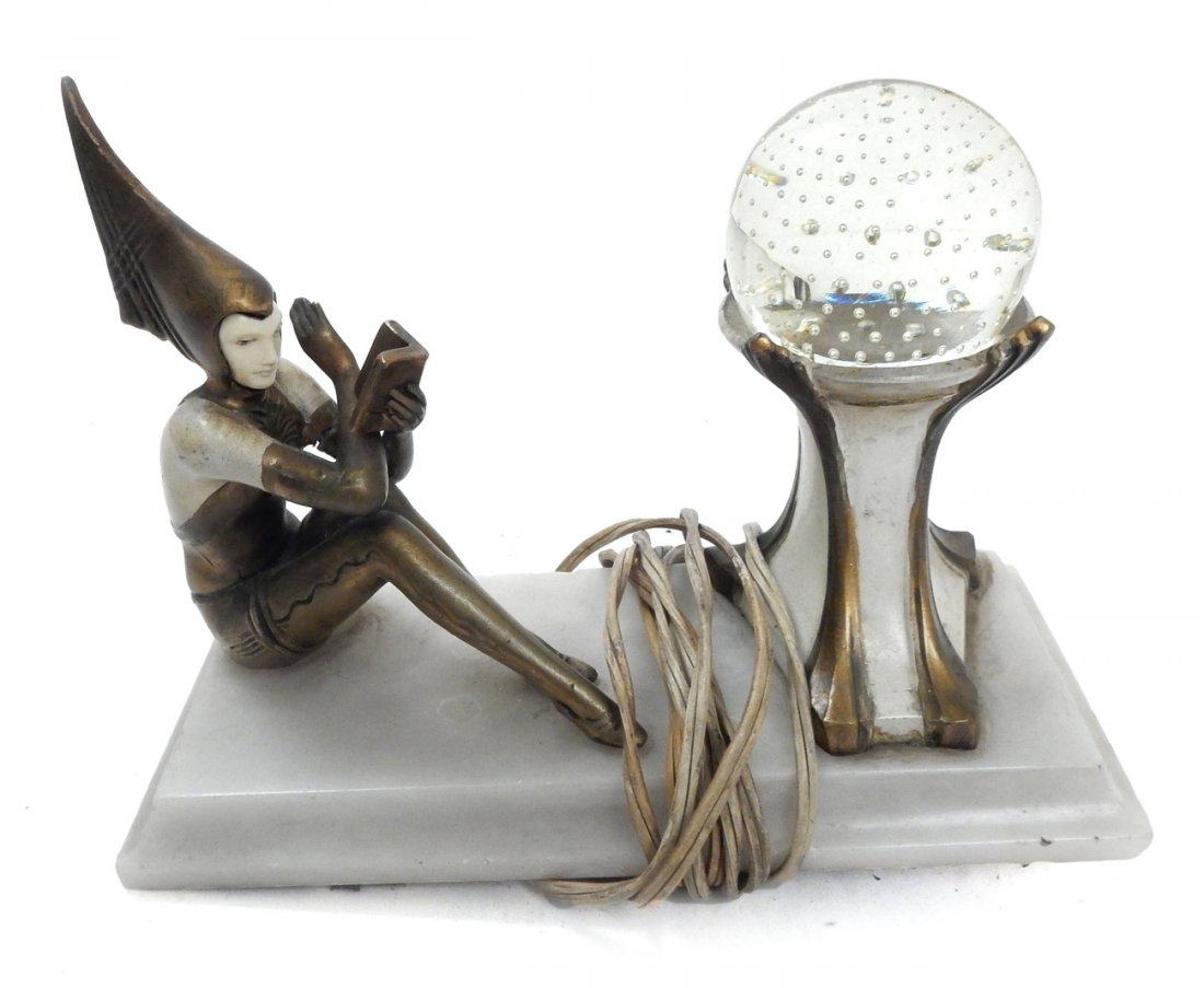 Art Deco Harlequin Lamp: Art deco lamp "Contemplar" with white metal harlequin seated figure reading a book, having a celluloid face on an alabaster base. [4 1/2" W x 10" L x 7 1/2" H]. Arm broken off and glass paperweight gl