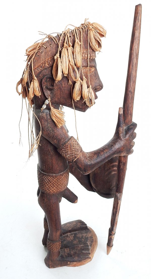 New Guinea Asmat Sculpture: New Guinea wood and rafia sculpture of a warrior with spear holding a man's head. Asmat carving. Ironwood from Agats, Irian Jaya. [6" x 9" x 23 1/4"]. In good condition.