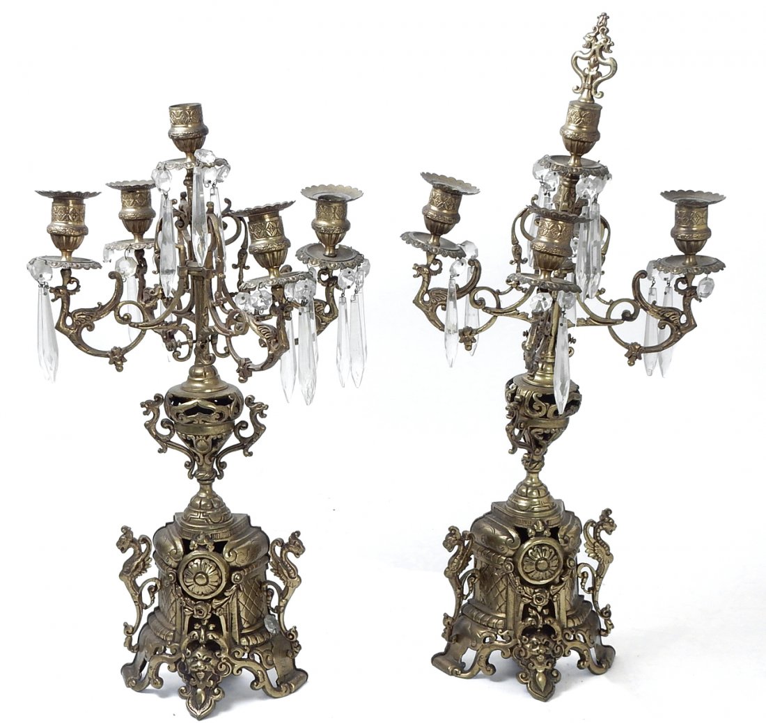Pair of Brass Candelabras: Ornate Asian cast brass candelabras with four arms and center candle holder. Spear prisms throughout (some missing). [10 1/4" Dia x 20 1/2" H]. Having some mismatched finials.
