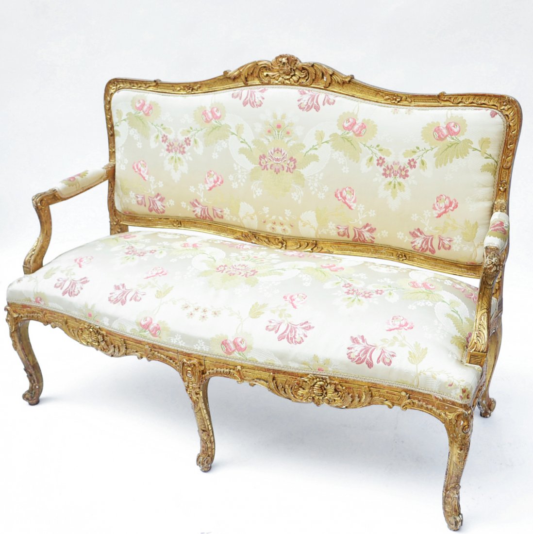 19th Century French Settee: 19th century French serpentine-form carved gilt wood settee, with floral upholstery. [55" W x 21" D x 39" H]. Some minor losses to gilt, otherwise in overall good condition.