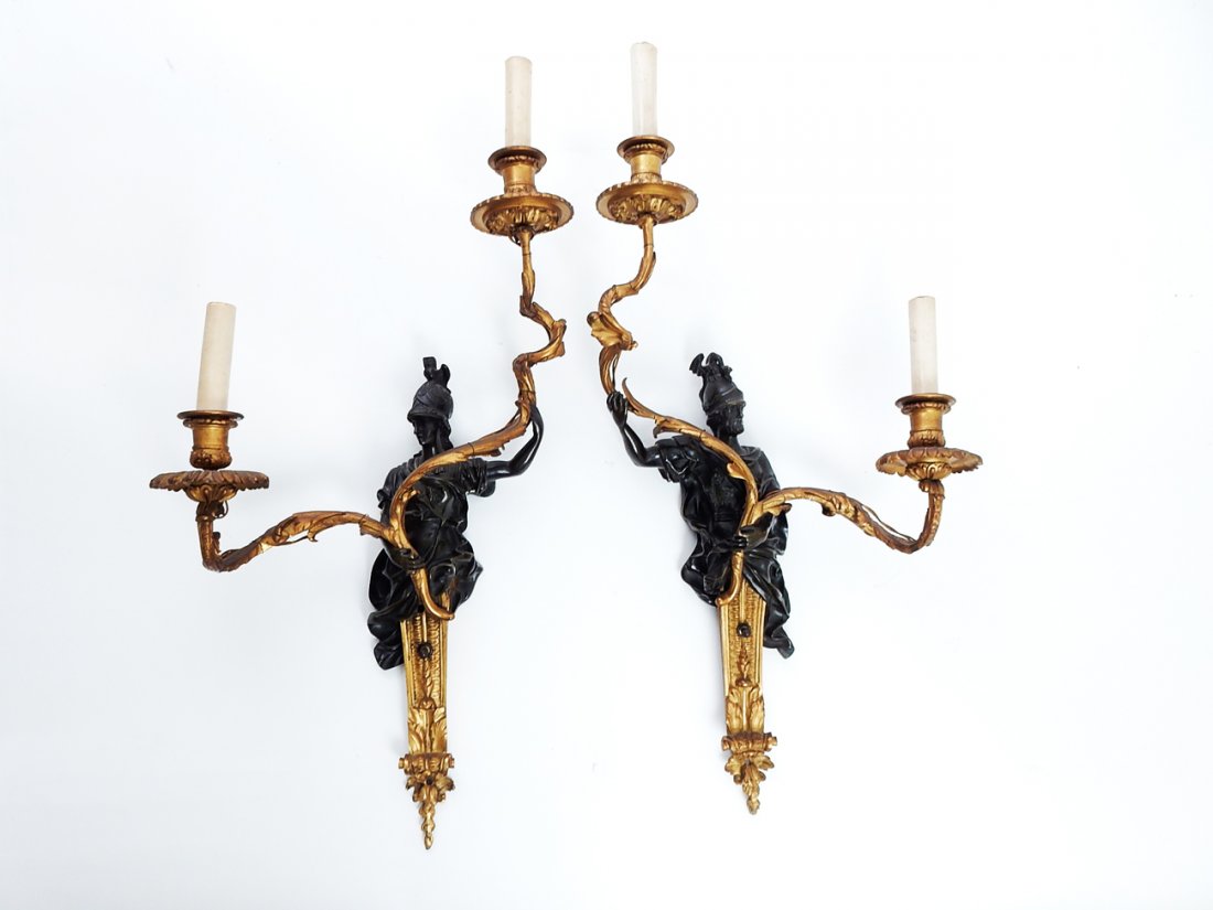 Pair of Figural Bronze Sconces: Baroque figural male and female bronze warrior two-arm ormolu sconces. [14" W x 6 1/2" D x 27" H]. Good condition.