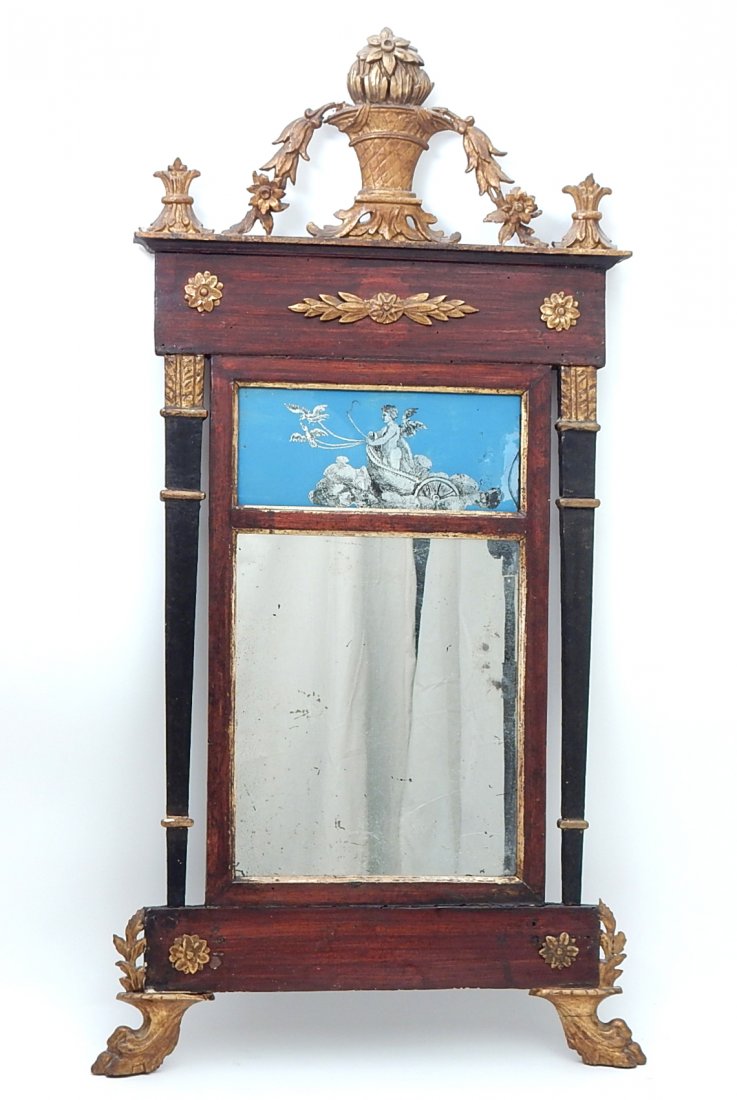 Antique American Eglomise Mirror: Antique mirror with a reverse painting on glass of a cherub in a chariot, rosette applique, carved feet, lacquered and gilt columns having a basket, floral, and bell flower crest.