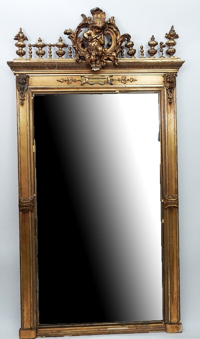 Gilt Pier Mirror: Antique beveled pier mirror having an ornate crest of a cherub playing a flute. [35 1/2" W x 65" H]. Damage especially to crest. Losses throughout.