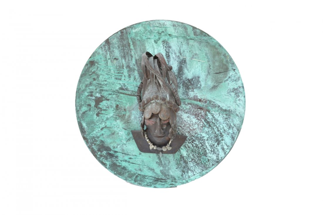 Copper Aboriginal Head: Copper aboriginal head with plumed headdress mounted on a copper circle with carved stone necklace. Verdigris patina. [Head: 26" x 10" x 8"; Mount: 41" diameter]. Heavily variegated.