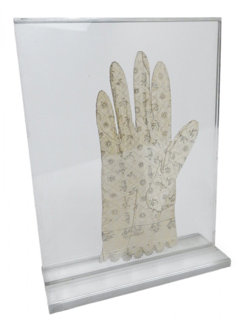 18th/19th Century Spanish Leather Glove: White leather glove with printed diaper pattern occupied by various figures, animals, and floral elements. Bears a dye-stamped cuff. [Glove: 4 1/2" W x 8 3/4" H"]. Contained between clear Lucite panel