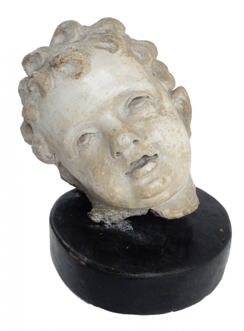 Antique Italian Plaster Child's Head: Antique classical-style plaster fragment, after Giacomo Serpotta, depicting the head of a child. [Head only: 7 1/2" W x 7 1/4" D x 7 3/4" H; with circular wood base: 9 3/4" H]. Soiling, wear, and chip