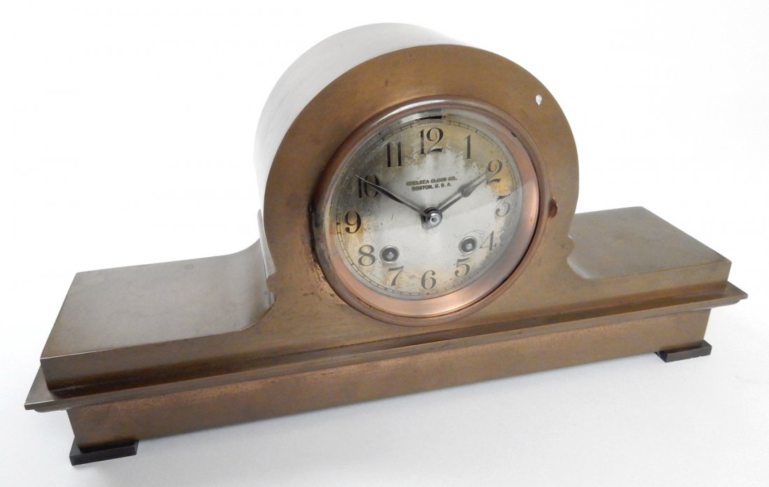 Chelsea Clock Co. Bronze Mantle Clock: Bronze case mantle clock with beveled crystal, cobber bezel, and silvered dialplate. Interior bears coil chime. [15 1/4" W x 3 7/8" D x 7 3/4" H]. Some scratches and wear to silvered dialplate. Not te