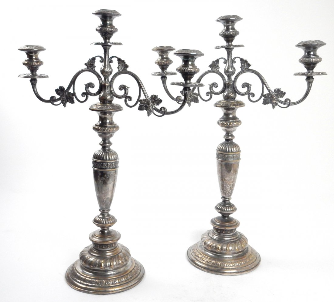 Pair of Antique Silver Plate Candelabra: Pair of three-light, two-branch Renaissance Revival candelabra. Features scrolling arms with leafy grape bunch accents. [17" W x 7 1/4" D x 23 1/2" H]. Finish worn and a few shallow dents.