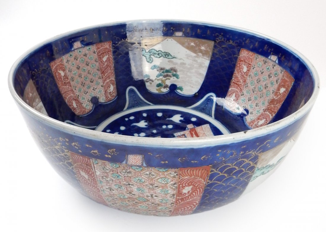 Japanese Porcelain Centerpiece Bowl: Antique Imari, gilt and enamel, circa 1900. Featuring mountain landscape and floral motifs. [16" Dia x 7" H]. Wear commensurate with age, generally good condition.