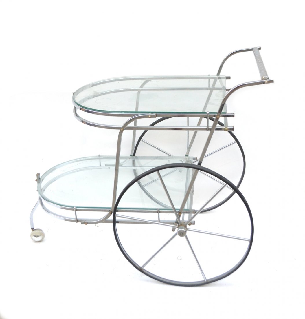 Modern Chrome and Glass Bar Cart: Traditional two-tier pennyfarthing-style bar cart composed of chromed steel with glass tops and brass accents. [21 3/4" W x 38" D x 33" H]. Some pitting and light oxidation.