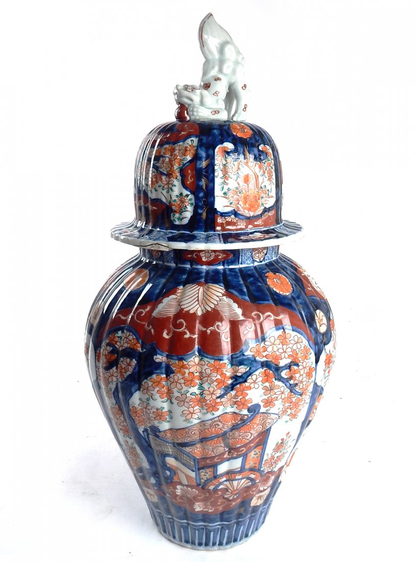 Imari Ginger Jar: Red, blue, and white decorated reed form covered ginger jar, having a foo dog finial cover. Top of the jar repaired, losses.