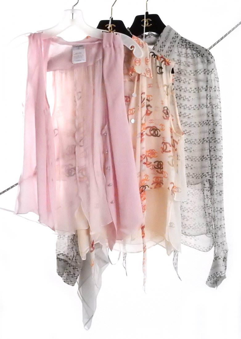 Three Chanel Women's Tops: 1.) Pink translucent top with pearl-like bead buttons bearing Chanel logo. Size 40 (Euro). Good condition. 2.) Tan translucent with orange, red, brown and gray Chanel logo patterns throughout. Size 40