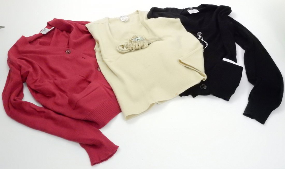 Three Chanel Cashmere Ladies Sweaters: 1.) Sleeveless soft yellow with central floral relief with beads. Size 38 (Euro). Slightly soiled. 2.) Long sleeve red button down with keyhole themed Chanel buttons. Size 42 (Euro). Good condition. 3