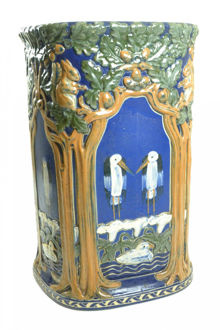 Ceramic Umbrella Stand: Glazed ceramic umbrella stand with tree, bird and squirrel motif. [14 1/2" W x 8" D x 22 1/2" H]. Hairline crack in front.