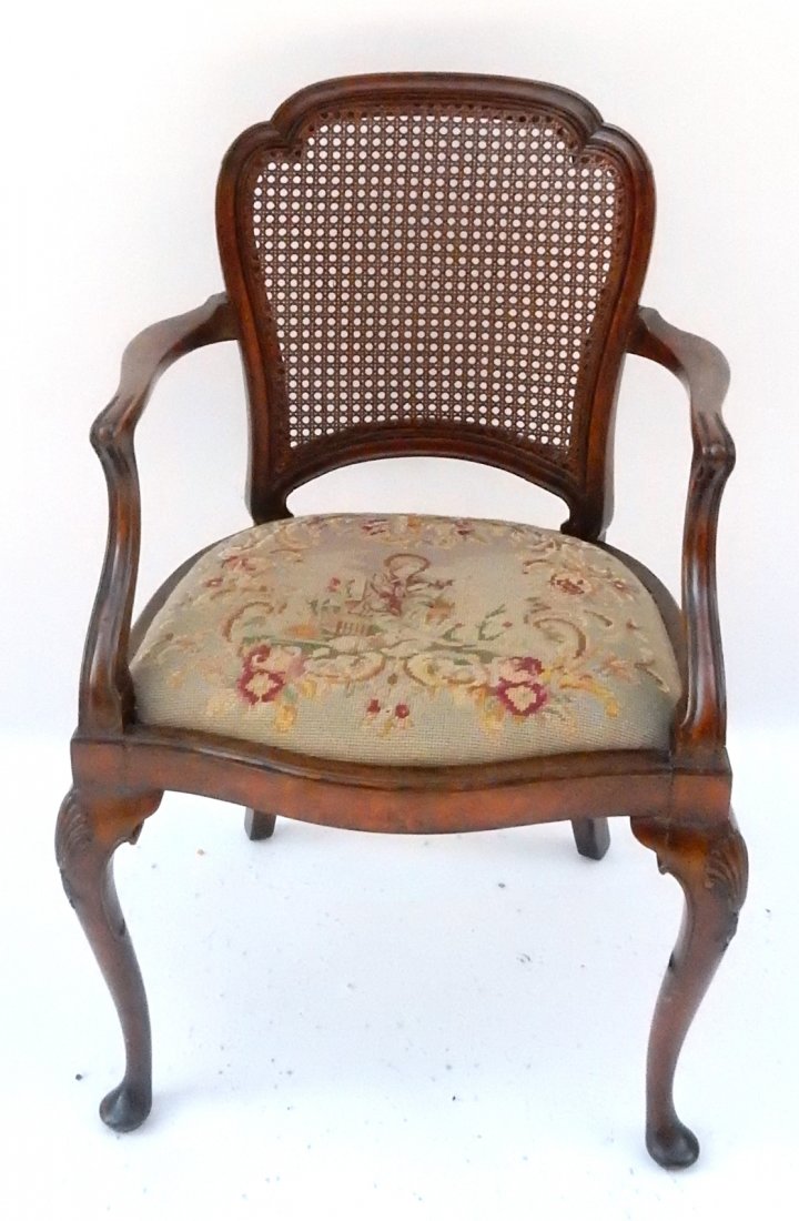 Cane Back Walnut Armchair, Shell Motif: Cane back armchair. Walnut with needlepoint seat, figure sitting. [22 1/2" W x 19 1/2" D x 33 3/4" H]. Good condition.