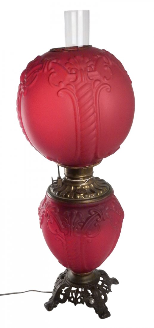 Antique "Gone With the Wind" Lamp: Electrified oil lamp with mould-formed cranberry glass reservoir and shade. [10" Dia x 26 1/2" H]. Wear to finish on metal hardware.