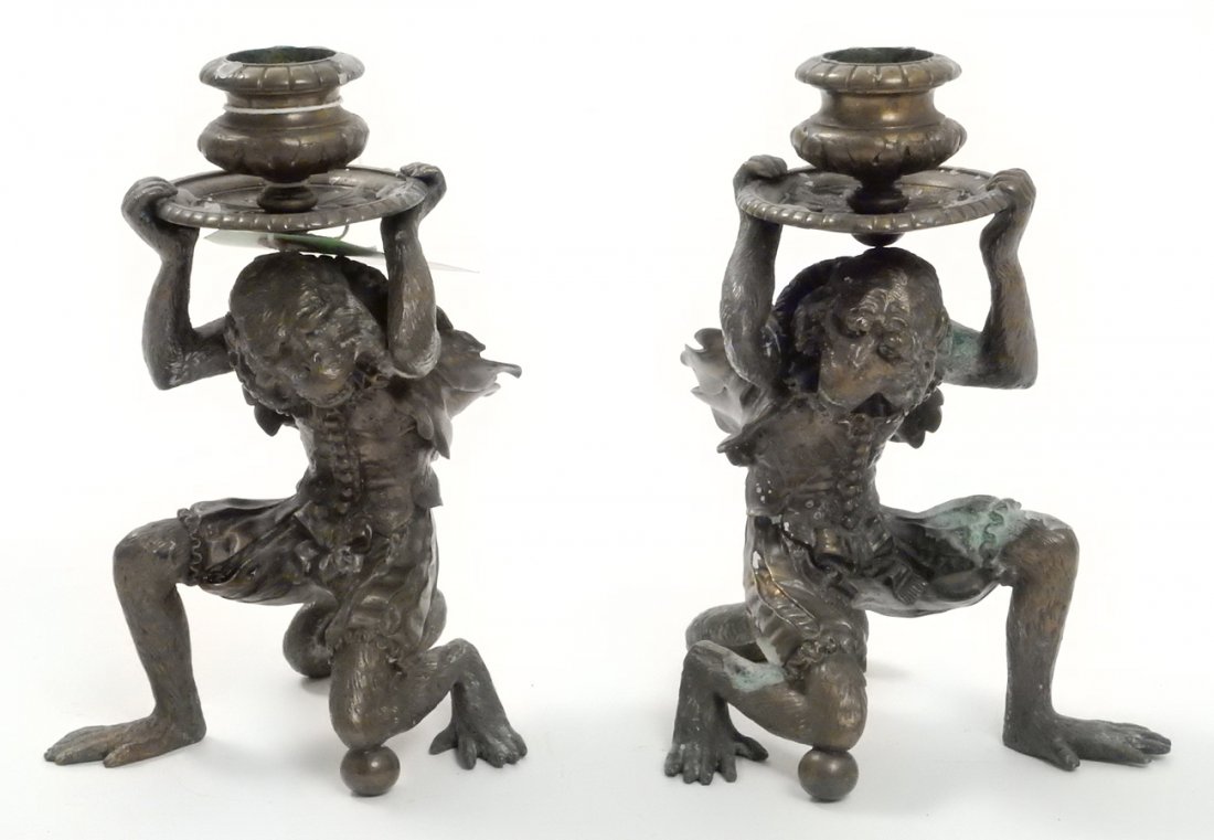 Pair Antique Bronze Monkey Candlesticks: Whimsical candlesticks with finely cast supports depicting kneeling monkeys in Renaissance costume. [4" W x 5" D x 6 1/8" H]. Uneven green patina.