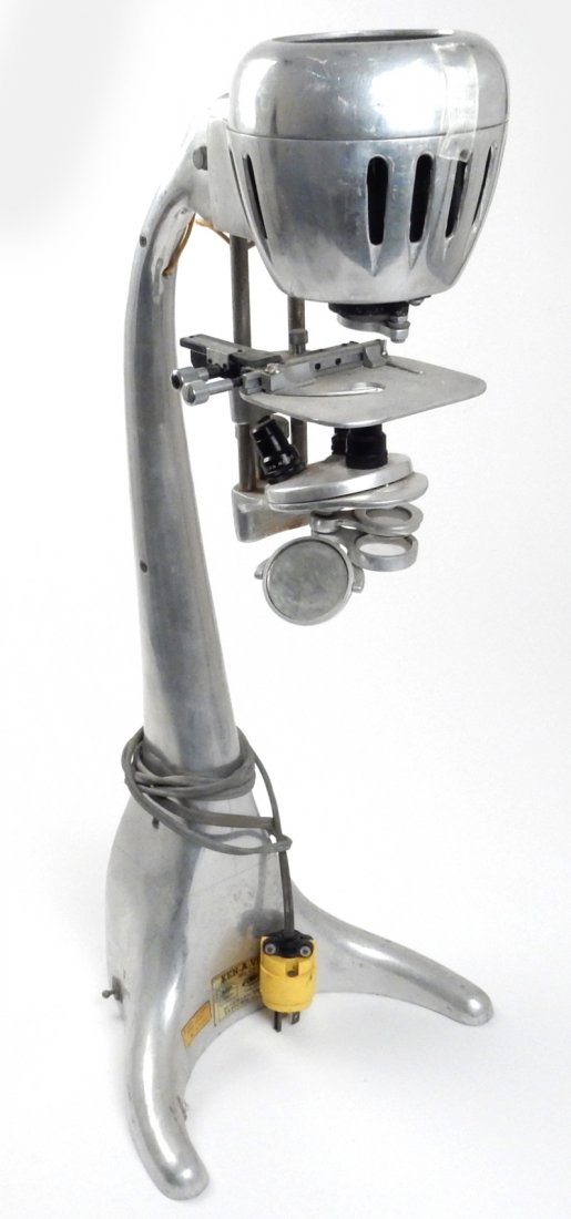 Ken-A-Vision Machine Age Micro-Projector: Vintage streamline aluminum body microscope projector. Bears gold foil label "Ken-A-Vision...Serial 7674...Raytown 33 Mo. USA" and a "Millbrae Elementary School..." label. [11" W x 10 1/2" D x 26" H].