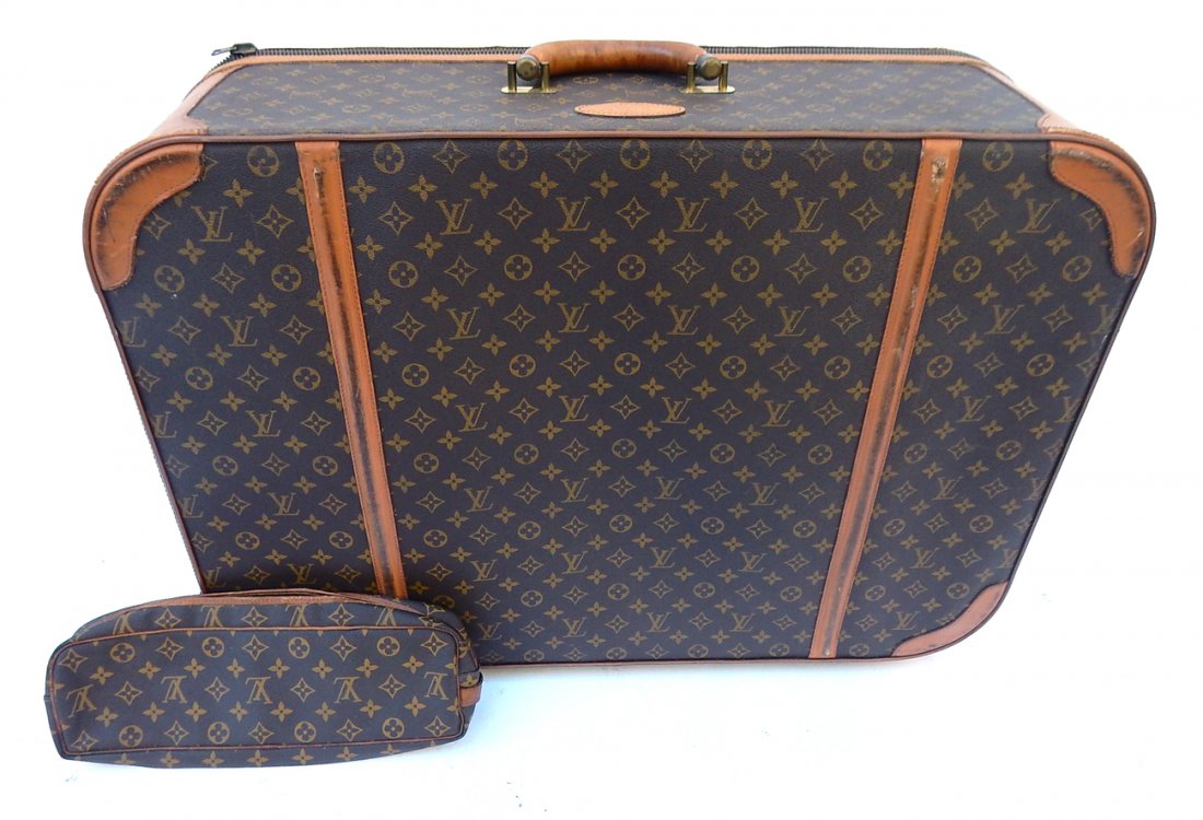 Louis Vuitton Suitcase: Brown suitcase with Louis Vuitton logo pattern throughout. Light brown leather trim. [29 3/4" W x 9 5/8" D x 21 1/8" H]. Fair condition, worn.