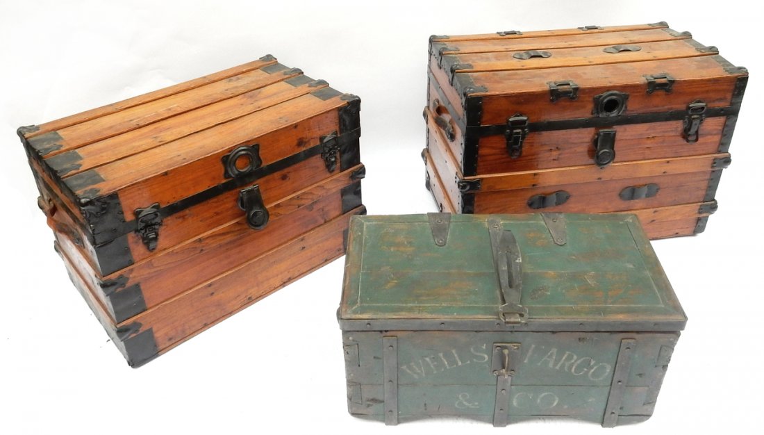 Three Wood Trunks: Three wood trunks, featuring metal bindings and straps. [Largest: 28" x 17" x 19 1/4"]. Wear to straps, one strap missing.