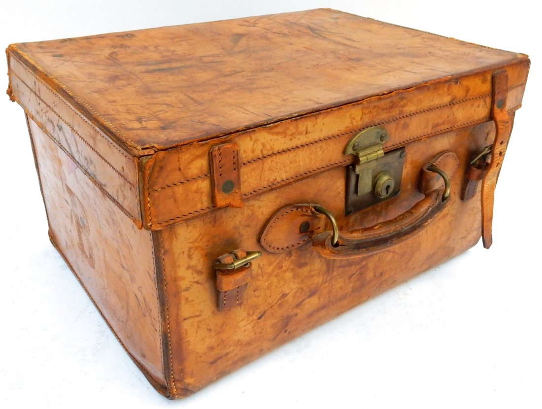Brown Leather Trunk/Suitcase: Brown leather trunk/suitcase with leather belt straps, handle, and lock. [19" x 10 1/2" x 14"]. Scratches throughout, one strap missing.