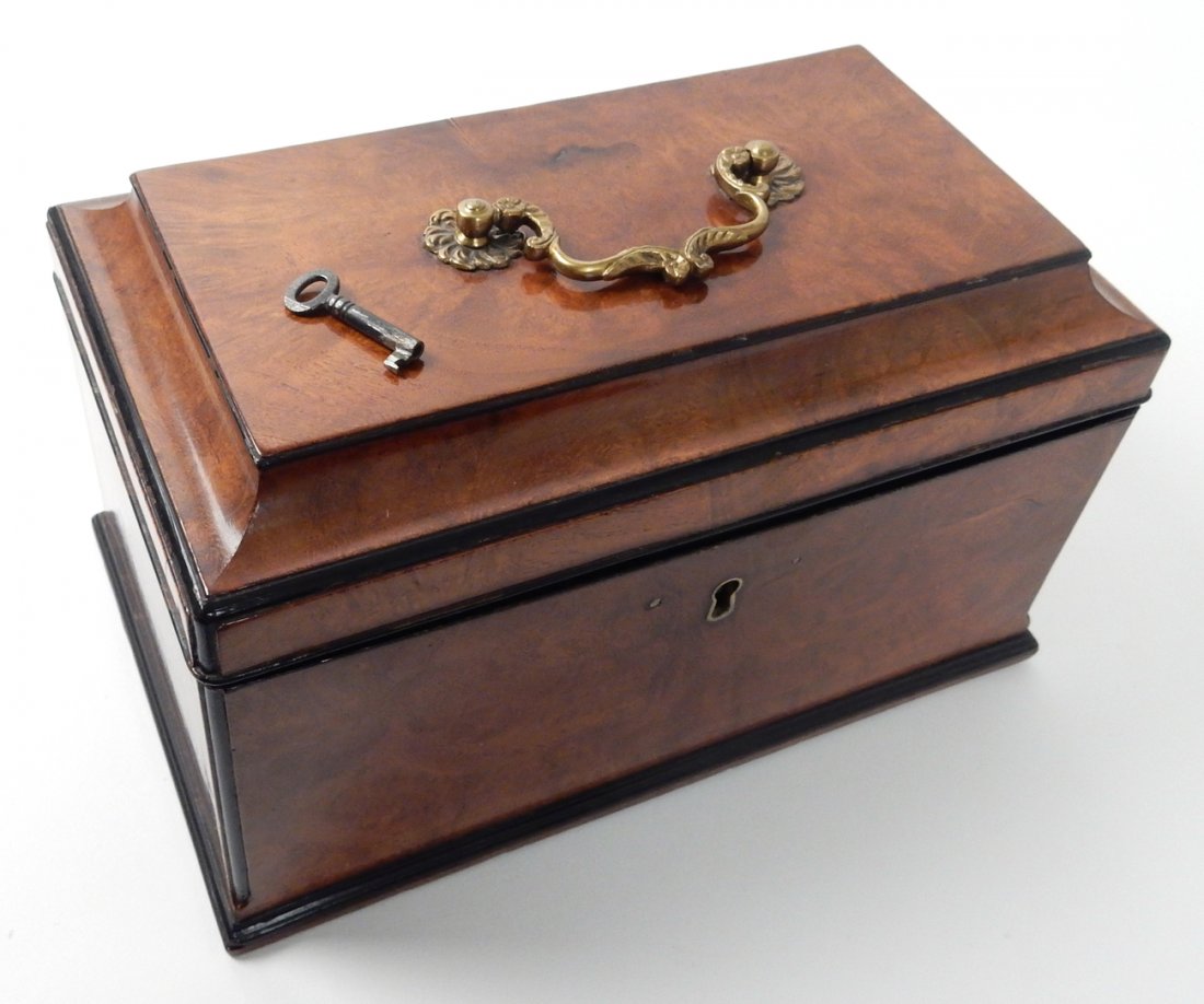 George III Burl Wood Tea Caddy: Rectangular tea caddy with animal brass handle and working key. Contrasting ebonized moldings. [10 3/4: W x 6 1/4" D x 6 1/4"]. Wear commensurate with age including very minor raising of veneer in bac