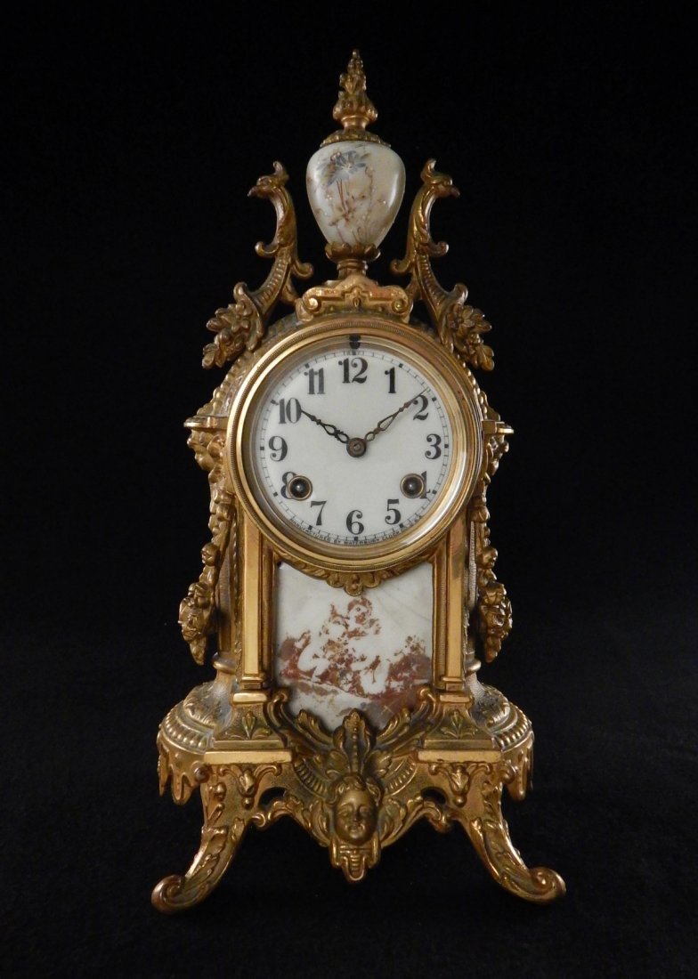 Bronze Mantel Clock: Marked "Manufactured by Watterbury Clock Co. U.S.A." on clock face, and bears label on bottom. [7" W x 5 3/4" D x 14" H]. Painted enamel facade caved in, nicks and light wear with age throughout.