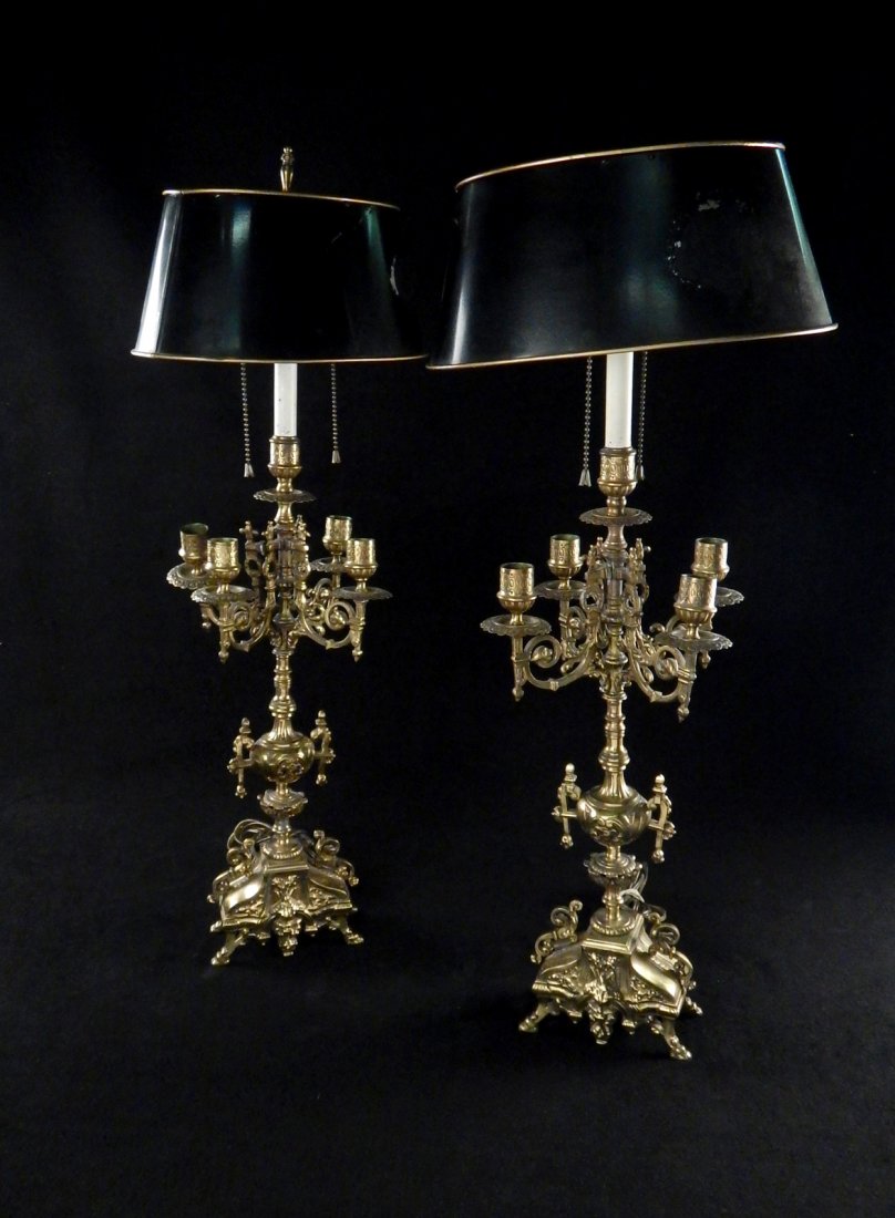 Pair of Brass Candelabra Table Lamps: Pair of four-arm candelabra table lamps with central light fixture and tole shade. [12" w x 8" D x 28" H]. Light wear throughout. One broken candelabra arm.