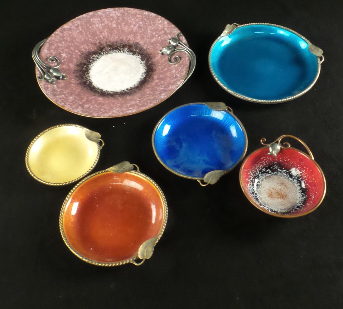 Six Enamel and Metal Trays: Six decorated enamel trays with appliques. In overall good condition.