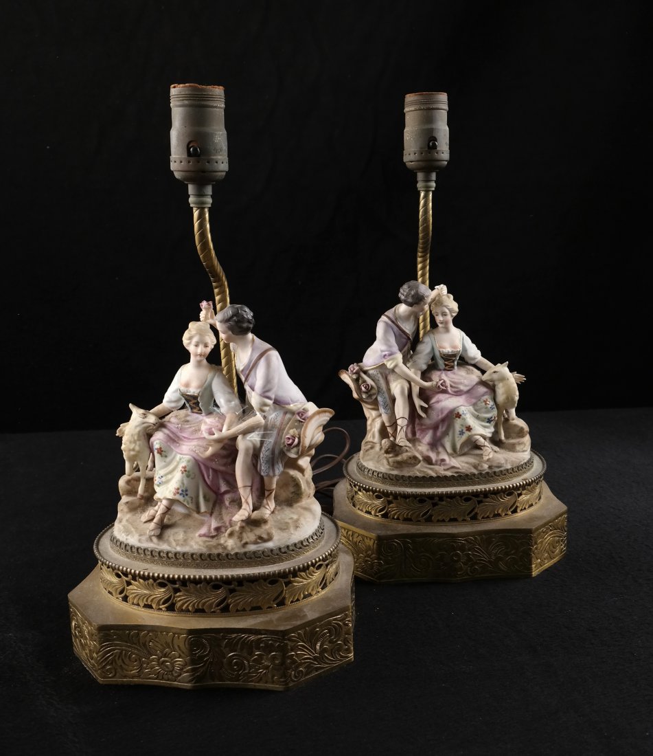 Pair of Bisque Figural Lamps: Pair of bisque figural lamps on brass bases. [Porcelain groups: 6" x 4" x 6" H; Overall dimensions: 7" x 6" x 14" H]. Hand broken with missing flower, arm broken off, bear old repairs. Both sold "as i