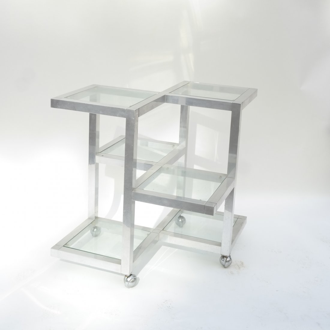 1960's-70's Modern Multi-Level Stand: Featuring square stock chrome frame with multiple levels, each with glass shelf. Mounted on casters. [29" x 29" x 31" H]. Light scratches and scuffs, consistent with age.