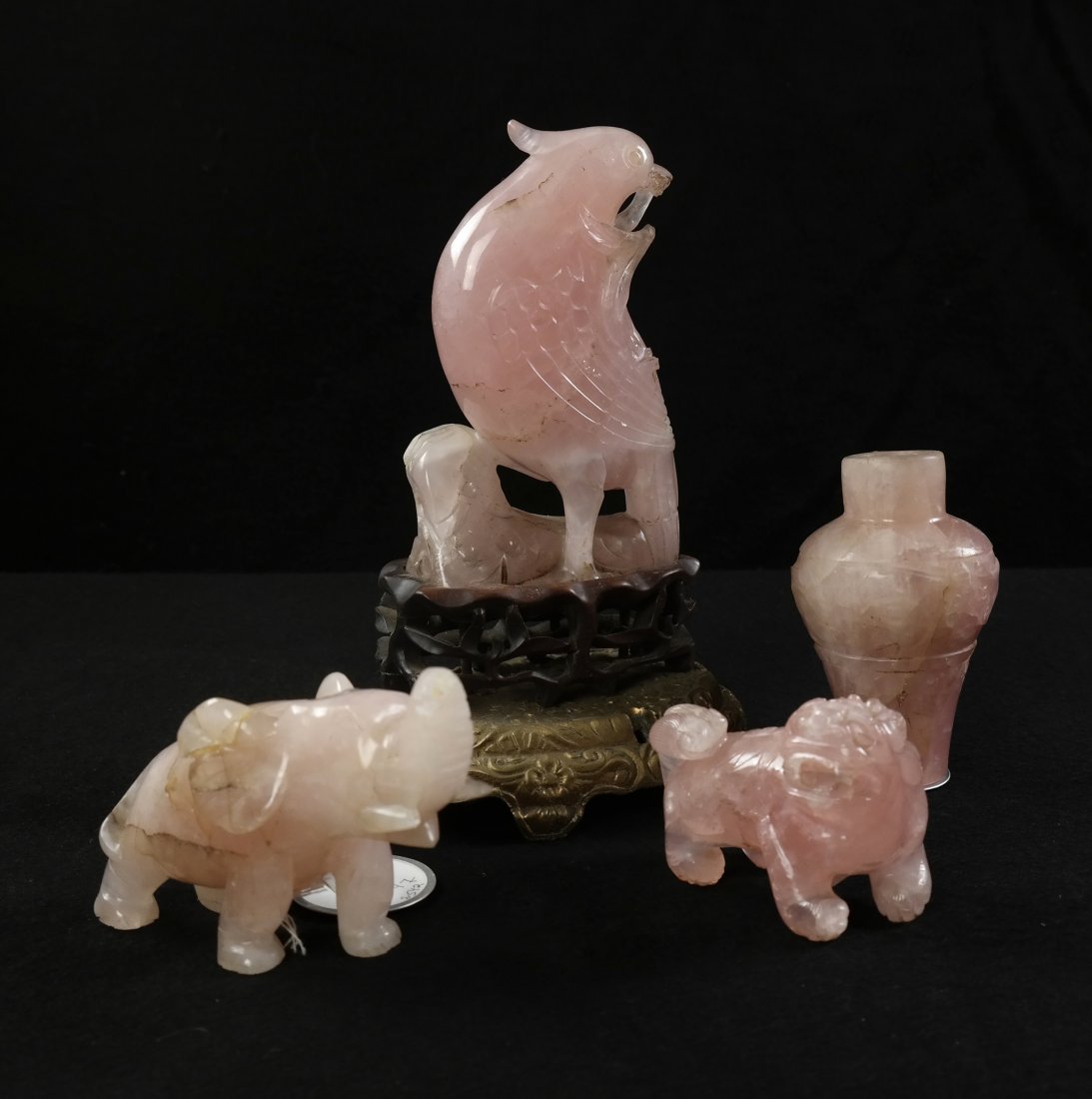 Four Carved Rose Quartz Figurines: Group of four rose quartz figurines comprising: 1.) Bird. [8 1/4" x 5 1/2"]. 2.) Elephant. [3" W x 2 1/4" H]. 3.) Foo Lion. [3" W x 2 1/4" H]. 4.) Vase. [2 1/2" Dia x 4"]. Bird damaged and elephant tu