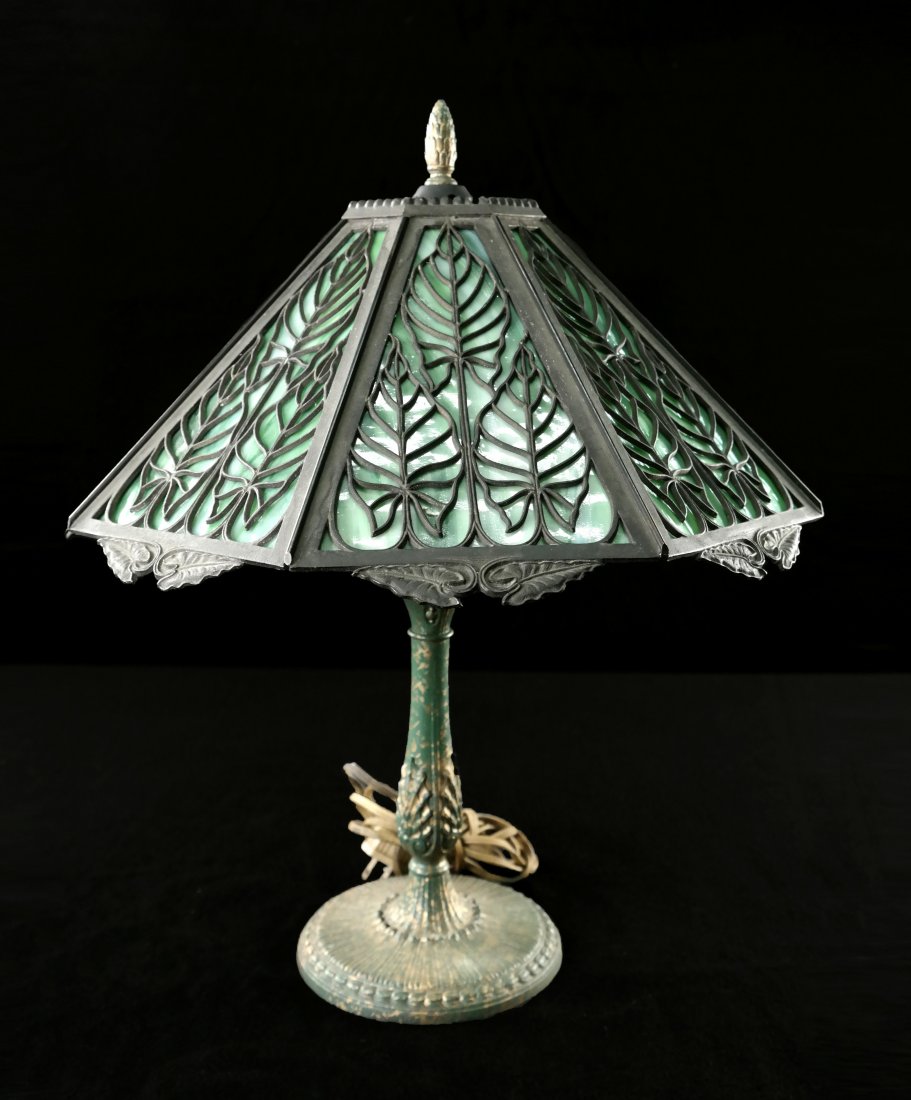 Arts & Crafts Style Lamp: Reticulated metal frame with foliate decoration and green slag glass panels on a patinated metal base. [15" Dia x 18" H]. Lacking support ring for shade.