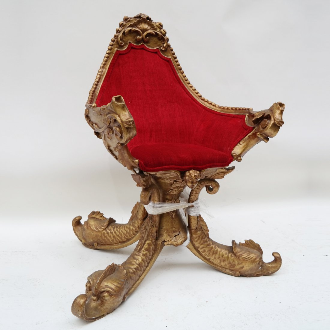 Venetian Ornate Grotto Chair: "Grotto" inspired carved and gilt wood arm chair with four dolphin legs and red velvet upholstered seat. [32" W x 27" D x 36" H (19" to seat)]. Base significantly damaged with multiple breaks.