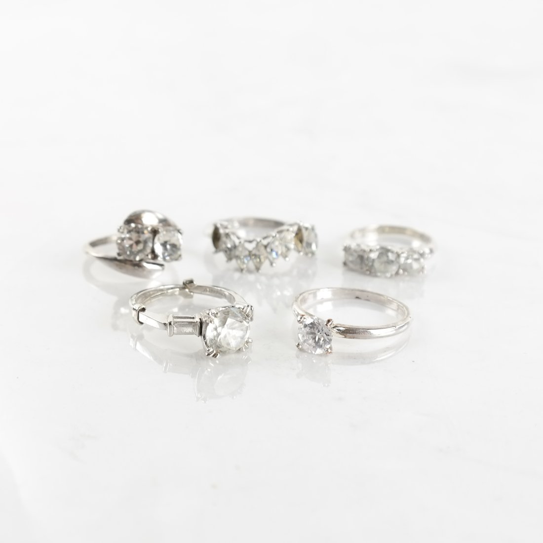 Five Various Rings: Five various simulated diamond and white metal rings. Includes two rings struck "14K" and "Kimberly", a ring struck "18k HGE", a sterling silver ring and a silver-clad ring, sizes [4 1/2 to 6 1/2]. Al