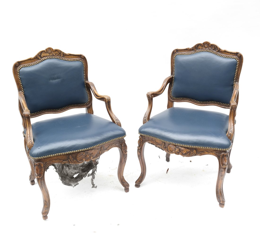 Pair of Louis XV-Style Fauteuils: Pair of Louis XV-style fauteuils, the crests and rails carved with stylized foliage, on four cabriole legs, later upholstered in blue leather. [25" W x 23" D x 38 3/4" H (crest)]. Shrinkage, cracks, w