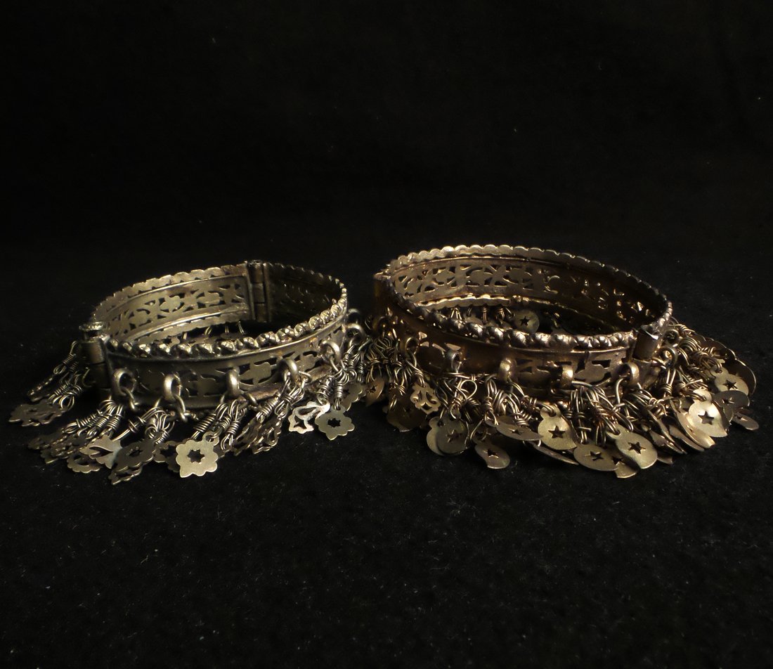 Pair of Pierced Metal Charm Bracelets: Pair of Mediterranean charm bracelets, each modeled as a hinged cuff with multiple charms. [3" Dia]. Bent, minor losses.