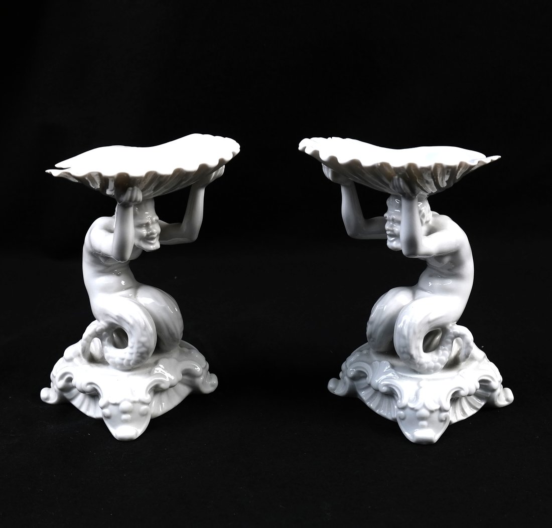 Pair of Italian Porcelain Figural Salts: Pair of 20th century Italian porcelain figural salts by Capodimonte. In 18th century style, each modeled as a merman holding a scallop shell aloft. Underglaze blue factory mark on bottom. [6" H x 4 1/