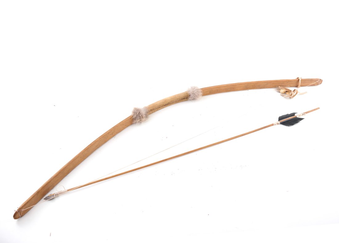 A Child's Bow and Arrow: Mid-20th century, the bent wood arrow with velum or parchment grip, the arrow with wood shaft and fitted with an arrowhead. [44 1/2" L and 36" L]. Each with some wear and minor losses.