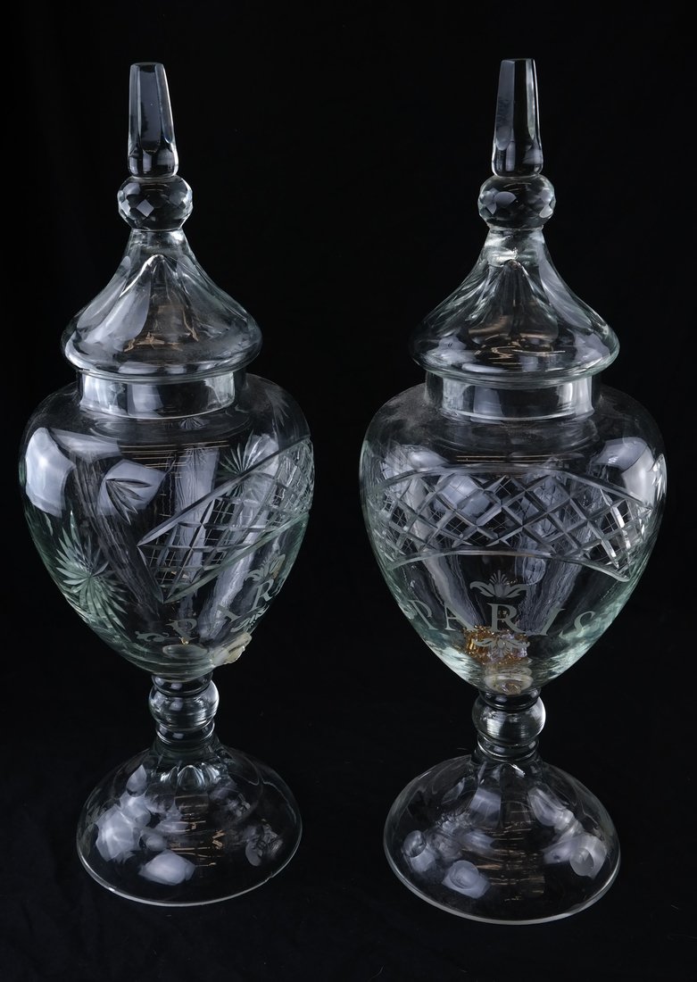 Pair of Large Glass Urns: Pair of large glass urns. "Paris" is etched on front of both. [26" H x 9 1/2" Dia]. Cracks and chips to both. Each drilled for spigot but lacking spigot.
