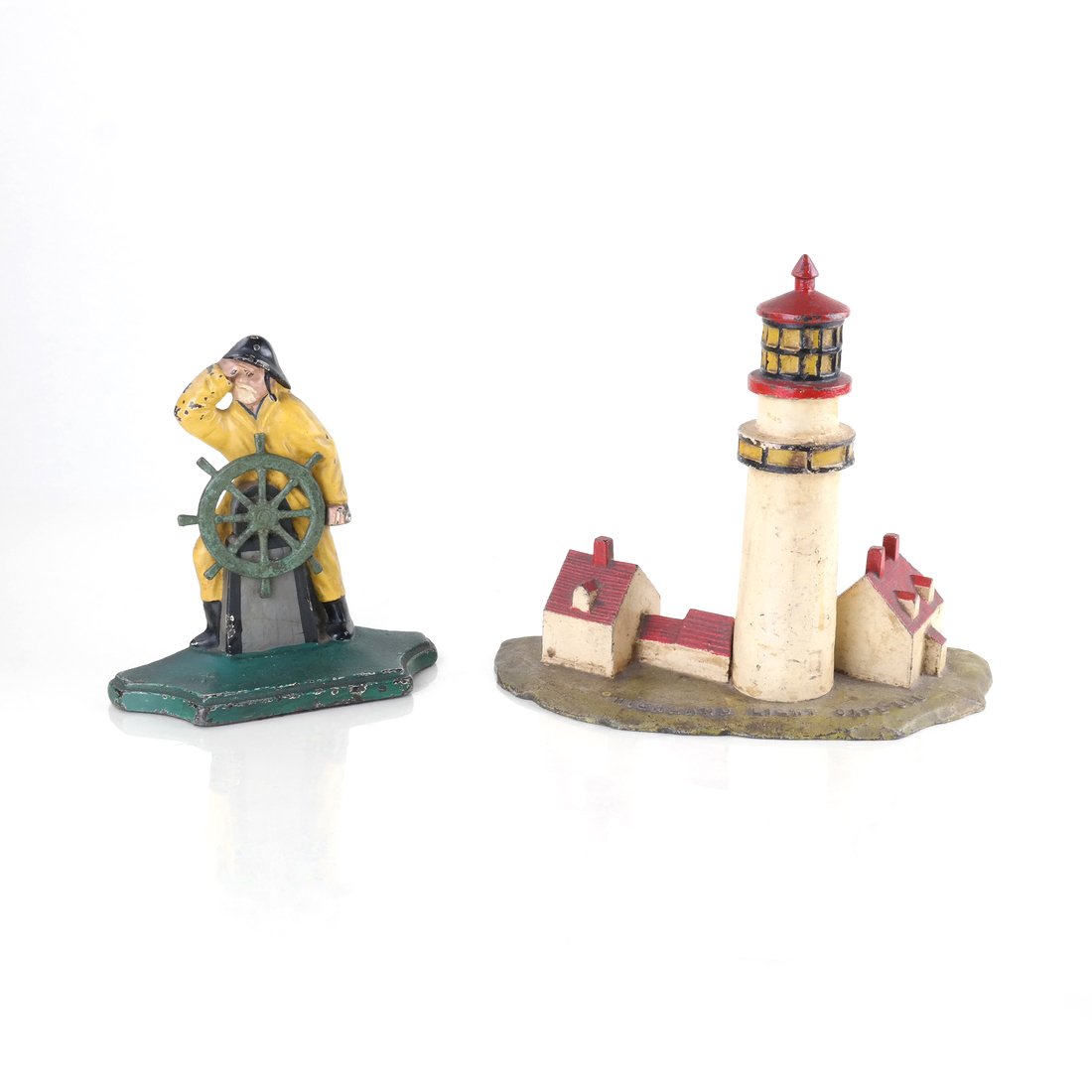 Two Painted Cast Iron Nautical Doorstops: Comprising: "Highland Light Cape Cod"[9" H x 7 3/4" W] and "Fisherman at Wheel" [6 1/4" H x 6" W].